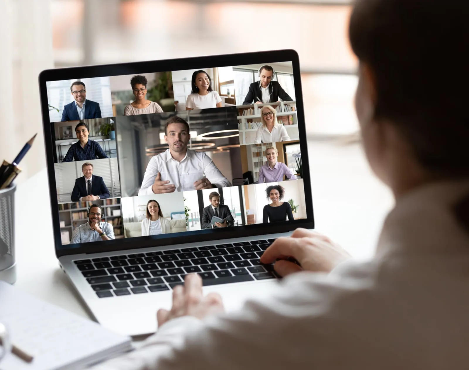 Person on a video call with a grid of meeting participants on a laptop