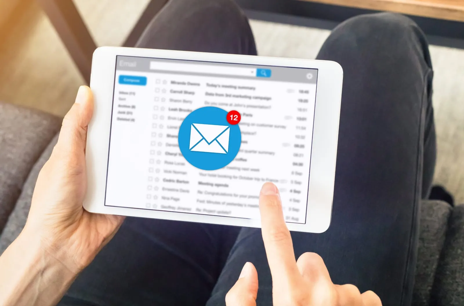 Hand tapping an email inbox on a tablet with a new-message notification icon